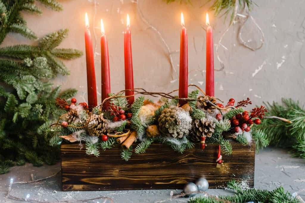 Elegant holiday candle centerpiece with pinecones, berries, and greenery.