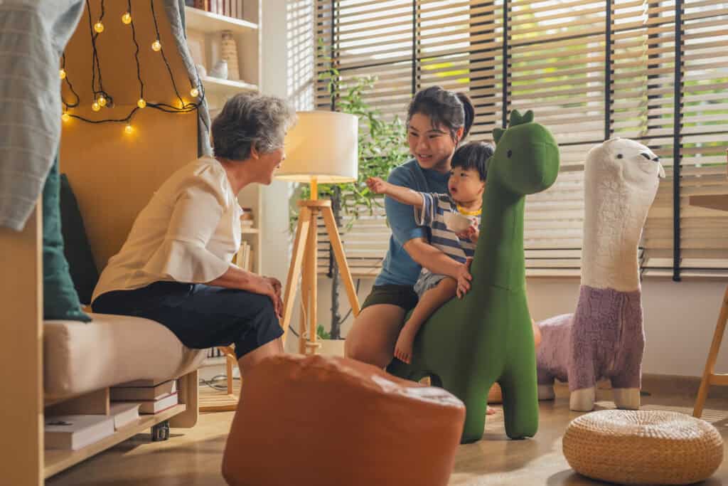 Family playing with large stuffed animals in a cozy, well-lit playroom.