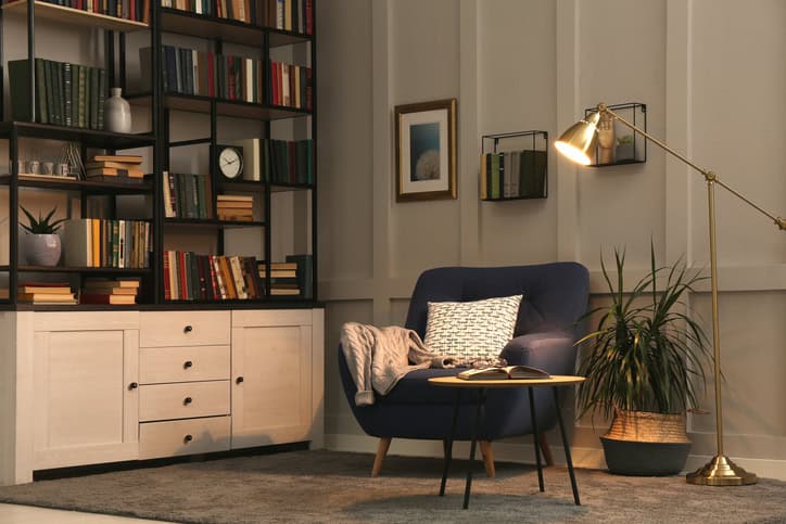 Cozy home library interior with collection of different books on shelves and comfortable place for reading