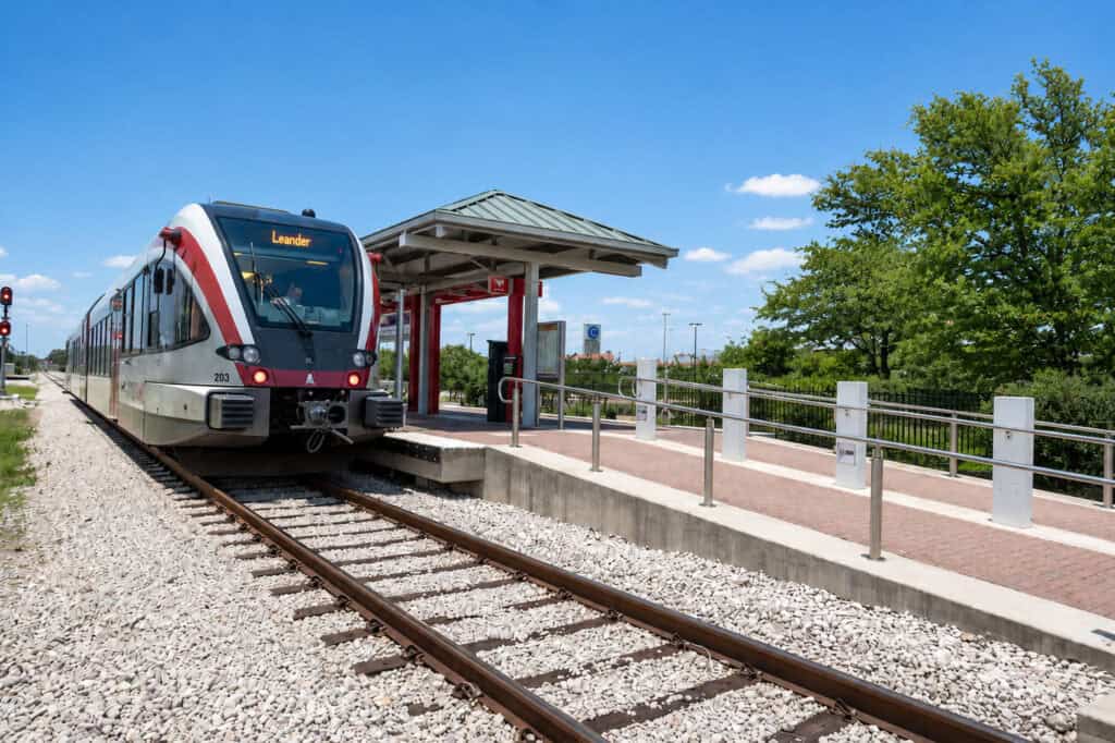 A modern commuter train at a small station platform in Travisso, Texas.