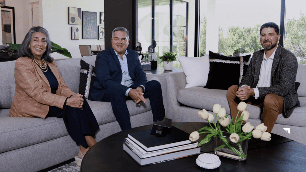 Three professionals sitting in a modern, well-lit office lounge area.