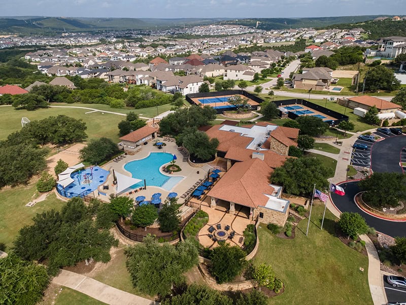 Aerial view of Travisso community with pool, tennis courts, and surrounding homes.