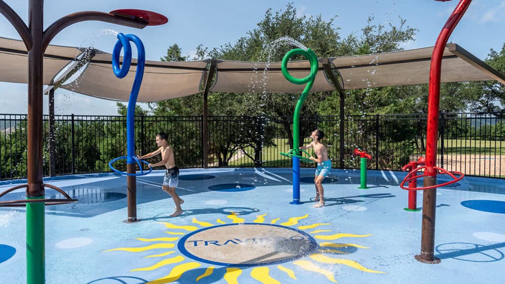 Children playing at the Travisso splash pad with colorful water features.